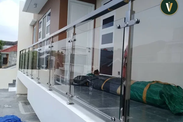 A metal railing with a glass top in front of a house.