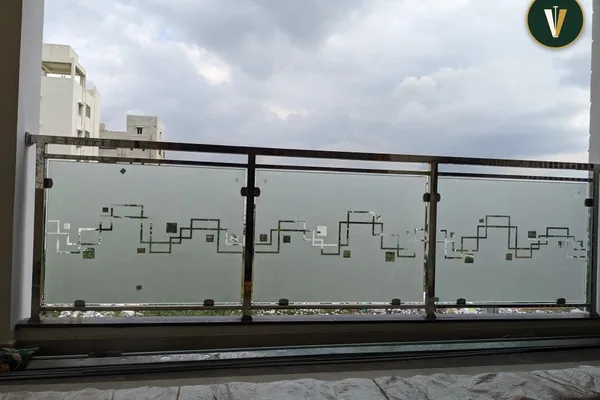 A glass balcony rail with a city skyline design in it.
