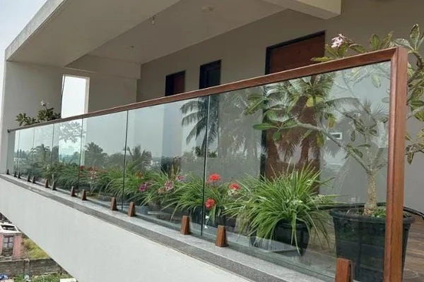 A balcony railing with a clear glass panel and wood frame.