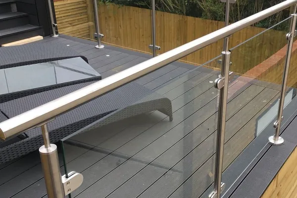 A frameless glass balcony railing with silver metal posts.