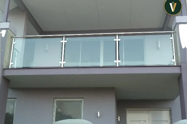 A glass balcony with metal railing and a view of the inside of a house.