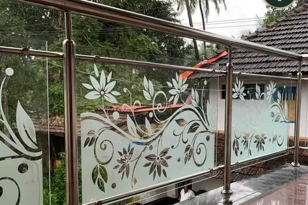 A glass and metal balcony railing with a floral design.