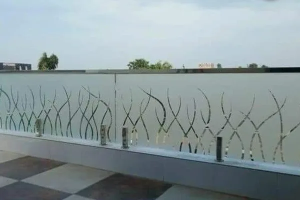 A glass balcony railing with curved designs and silver hardware.