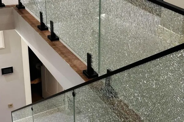 A staircase railing with a glass top and black metal frame.