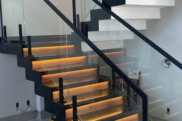 A black and glass staircase with yellow lights.