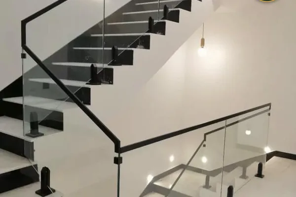A glass and metal staircase with a rail and lighting.