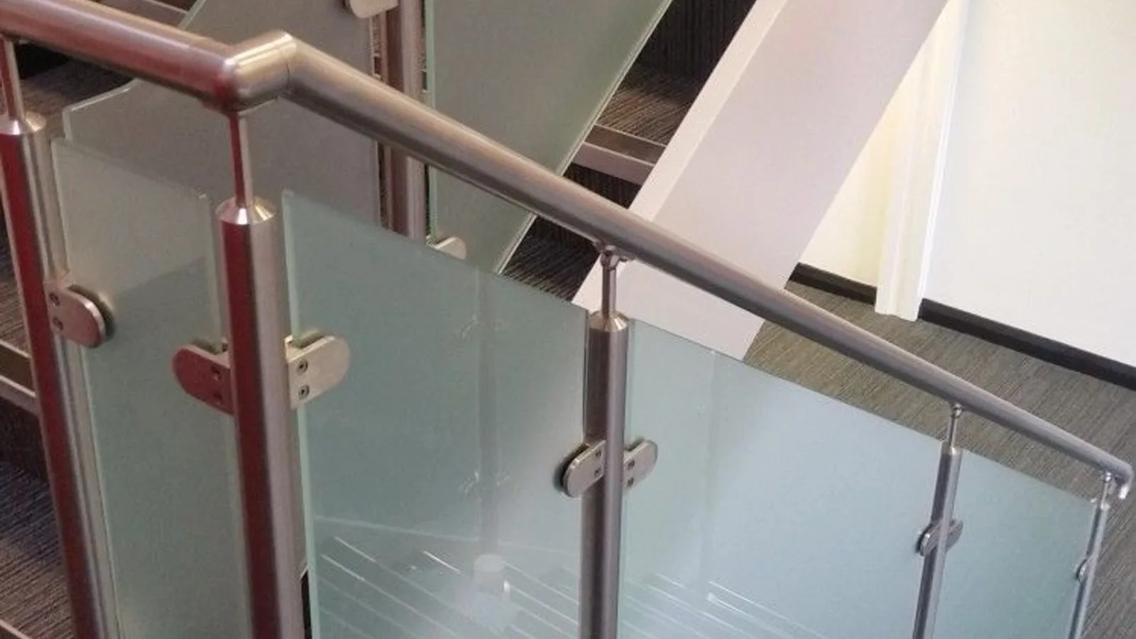 A staircase with a glass hand rail at the top.