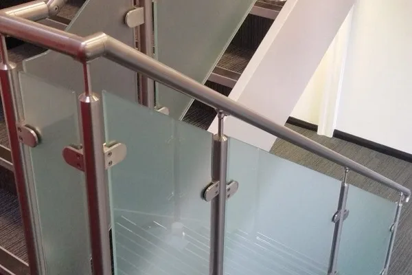 A staircase with a glass hand rail at the top.