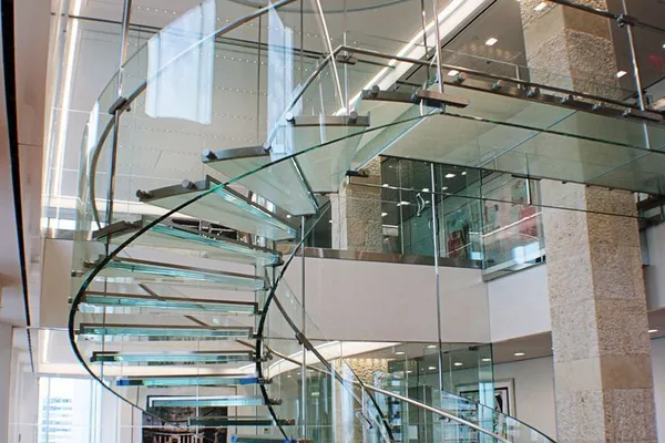 A glass staircase with a spiral design in a room.