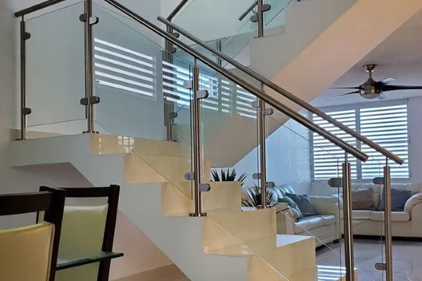 A glass staircase with metal railing and a white couch in the background.