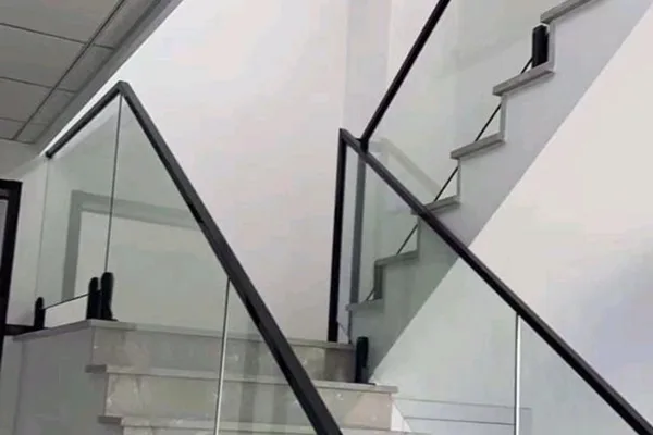 A glass staircase with black metal railing.