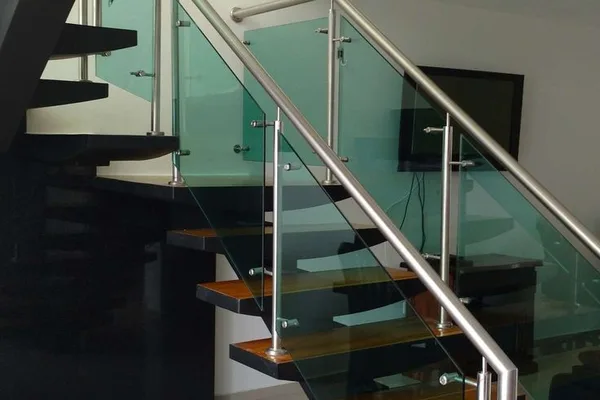 A glass staircase with metal railing and a TV in the background.