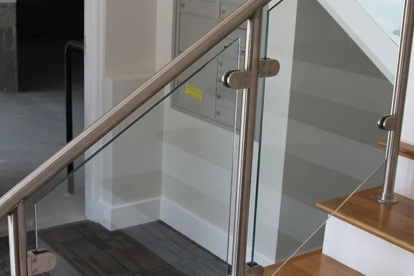 A staircase with a metal hand rail, glass steps, and a mailbox on the wall.