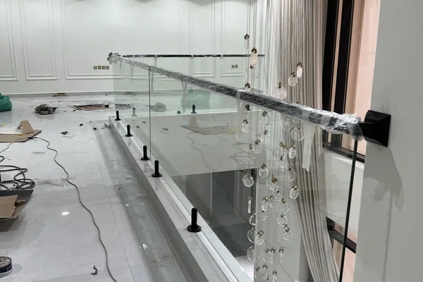 A glass staircase with a white wall and a glass balcony.