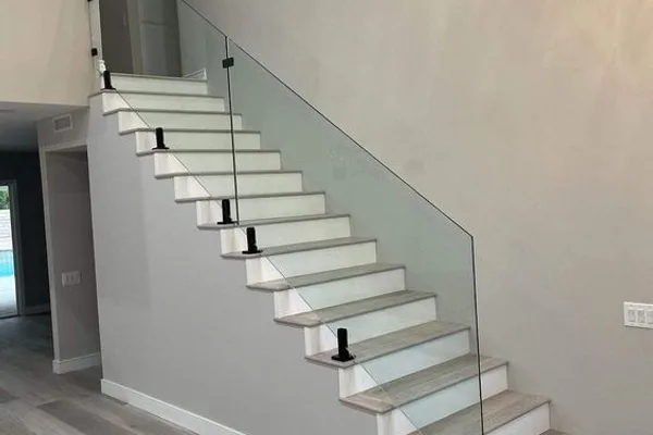 A glass staircase with a white frame and black bottoms.